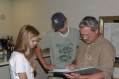 Heather Smith, Tyler Strange, and Mike Lucas look at photos from last convention
